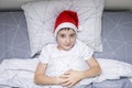 A preteen boy lying in bed in santa hat during christmas eve night and waiting for gifts and miracles, happy xmas and new year Royalty Free Stock Photo