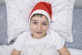 A preteen boy lying in bed in santa hat during christmas eve night and waiting for gifts and miracles, happy xmas and Royalty Free Stock Photo