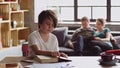 Preteen boy reading book while his parents relaxing on sofa in background Royalty Free Stock Photo