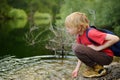 Preteen boy in red shirt is exploring nature and playing with water in lake during hiking in mountains valley. Active leisure for Royalty Free Stock Photo