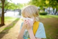 Preteen boy sneezing and wipes nose with napkin during walking in summer park. Flu season and cold rhinitis. Allergic kid Royalty Free Stock Photo