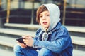 Preteen boy using smartphone at school outside. Smart boy playing game on phone. Schoolboy taking break using mobile Royalty Free Stock Photo