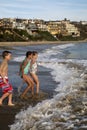 Preteen children playing at the beach running into waves