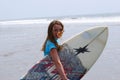 Preteen girl carrying a surfboard to the ocean