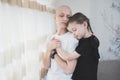 Preteen girl embracing sick hairless mother with oncology. Portrait of ill woman patient after chemotherapy hugging Royalty Free Stock Photo