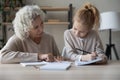 Preteen girl listen to mature grandmother get help with homework