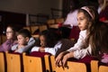 Preteen girl with other children absorbedly watching movie in cinema