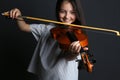 Preteen girl playing violin on black background, focus on hand Royalty Free Stock Photo