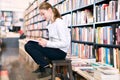 Preteen girl sitting on step ladder in library Royalty Free Stock Photo
