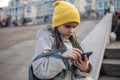 Preteen girl sitting on street stairs and texting with smartphon