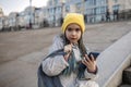 Preteen girl sitting on street stairs and texting with smartphon