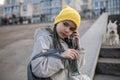 Preteen girl sitting on street stairs and texting with smartphon