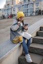 Preteen girl sitting on street stairs and texting with smartphon