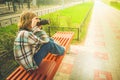 Preteen girl taking pictures of something with a SLR camera while sitting on a bench Royalty Free Stock Photo