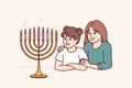 Preteen girls sisters look at menorah with burning candles and rejoice at approach holiday hanukkah