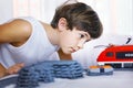 Preteen handsome boy play with meccano toy train and railway sta