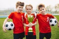 Preteen happy soccer players after final game. Boys holding golden cup and soccer balls