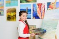 preteen kid holding palette near canvas in workshop of Royalty Free Stock Photo