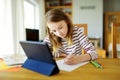 Smart preteen schoolgirl doing her homework with digital tablet at home. Education and distance learning for kids. Homeschooling Royalty Free Stock Photo