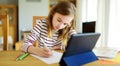 Smart preteen schoolgirl doing her homework with digital tablet at home. Education and distance learning for kids. Homeschooling Royalty Free Stock Photo