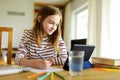 Smart preteen schoolgirl doing her homework with digital tablet at home. Education and distance learning for kids. Homeschooling Royalty Free Stock Photo