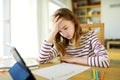 Smart preteen schoolgirl doing her homework with digital tablet at home. Education and distance learning for kids. Homeschooling Royalty Free Stock Photo