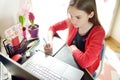 Preteen schoolgirl doing her homework with laptop computer at home. Child using gadgets to study. Online education and distance Royalty Free Stock Photo