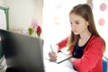 Preteen schoolgirl doing her homework with laptop computer at home. Child using gadgets to study. Online education and distance Royalty Free Stock Photo