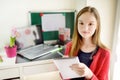 Preteen schoolgirl doing her homework with laptop computer at home. Child using gadgets to study. Online education and distance Royalty Free Stock Photo