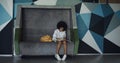 Preteen schoolgirl doing homework in hall. African american girl sitting bench. Royalty Free Stock Photo