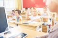 Preteen schoolgirl raising hand to answer during lesson Royalty Free Stock Photo