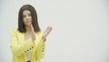 Pretentious brunette woman in yellow formal suit clapping, and looking annoyed over white background