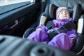 Prette toddler child sleeping in an infant safety seat in a car on back passenger seat, window season Royalty Free Stock Photo