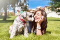 Pretty adult caucasian happy woman resting in the park on a sunny day with her beloved dog. Female lies on the grass, smiling and Royalty Free Stock Photo