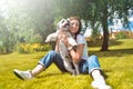 Pretty adult caucasian happy woman resting in the park on a sunny day with her beloved dog. Female lies on the grass, smiling and Royalty Free Stock Photo