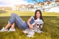 Pretty adult caucasian happy woman resting in the park on a sunny day with her beloved dog. Female lies on the grass, smiling and Royalty Free Stock Photo