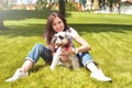 Pretty adult caucasian happy woman resting in the park on a sunny day with her beloved dog. Female lies on the grass, smiling and Royalty Free Stock Photo