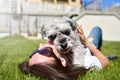 Pretty adult caucasian happy woman resting in the park on a sunny day with her beloved dog. Female lies on the grass, smiling and Royalty Free Stock Photo