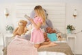 Pretty adult girl with her secret diary in her white bedroom with many plush teddy bears