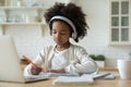 Pretty African American little girl wearing headphones studying at home Royalty Free Stock Photo