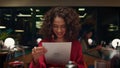 Pretty african american woman choosing looking menu at fancy restaurant table. Royalty Free Stock Photo