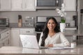 A smiling woman works from her home office in her kitchen