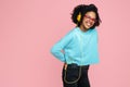 Pretty african american young woman with bright smile listening music in headphones over pink background. Royalty Free Stock Photo