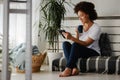 Pretty African American young woman reading an eBook at home Royalty Free Stock Photo