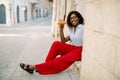 Pretty African smiling lady having lunch time outdoor in old European city. African American smiling woman tourist Royalty Free Stock Photo