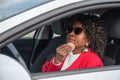 Pretty african woman in a car doing makeup while standing in a traffic jam Royalty Free Stock Photo