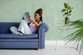 Pretty African young woman reading magazine and smiling while sitting on the sofa in a comfortable pose in a living room Royalty Free Stock Photo