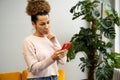 A pretty African young woman uses a smartphone, smiles, looks at the screen, reads SMS messages Royalty Free Stock Photo