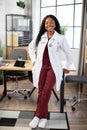 Pretty Afro-American woman doctor, posing to camera with happy smile in modern office Royalty Free Stock Photo