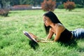 Pretty afro american woman reading book lying in grass in park Royalty Free Stock Photo